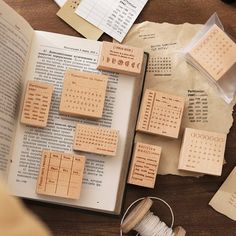 several pieces of wood sitting on top of an open book next to spools of thread