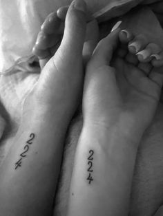 two people with matching tattoos on their arms and feet, both holding each other's hands