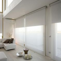 a living room with white furniture and large windows