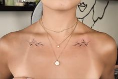 a woman with two small tattoos on her chest and one is wearing a gold necklace