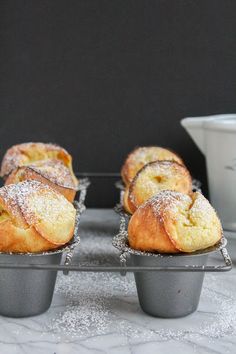 three muffins sitting on top of each other in pans covered in powdered sugar