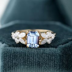 a blue and white stone ring sitting on top of a velvet box with its lid open