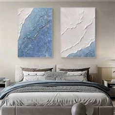 two paintings on the wall above a bed in a room with white and blue decor