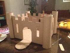 a castle made out of cardboard sitting on top of a table next to a plate of food