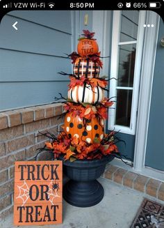 a halloween decoration with pumpkins and other decorations on the front porch, next to a trick or treat sign