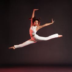 a woman in white pants and pink top doing a dance move with her arms outstretched