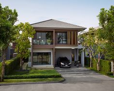 a car is parked in front of a two story house with trees and bushes around it