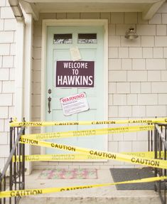 yellow caution tape blocking off the front door of a house with a welcome to hawks sign on it