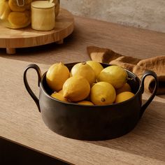 a bowl filled with lemons on top of a wooden table