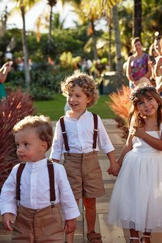 two little boys and one girl are walking down the sidewalk with their hands in each others'pockets