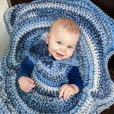 a baby wrapped in a blue and white crocheted blanket