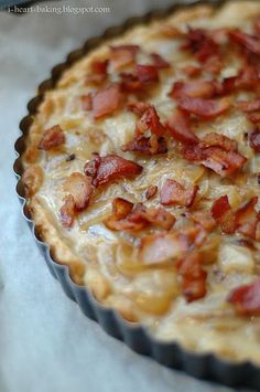 a bacon and cheese quiche sitting on top of a paper towel in a pie pan