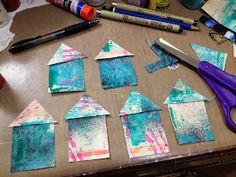 paper houses are cut out and placed on a table with craft supplies next to them