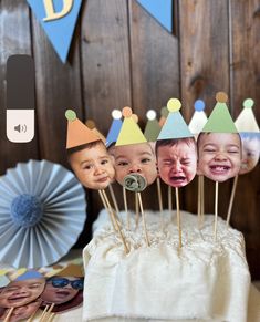 a cake topped with pictures of babies wearing hats and holding sticks in front of them