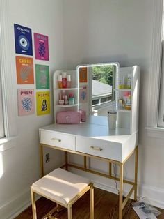 a desk with a mirror, stool and pictures on the wall in front of it