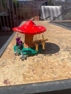 two small figurines are sitting on a table next to a red mushroom house