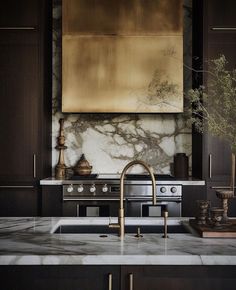 a kitchen with marble counter tops and dark wood cabinets, gold foiled artwork on the wall