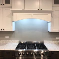 a stove top oven sitting inside of a kitchen next to white cupboards and counter tops