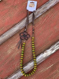 Lucille Mulhall is the epitome of a cowgirl! She was feminine, soft spoken, and well educated, and seemed a paradox. This beautiful necklace embodies this all around cowgirl by being just that! This beautiful one strand necklace boast elegant green turquoise beads. Dark brown heishi beads draw out the tan and brown specks in the turquoise beads and make the hand tooled pendant pop! Dark brown leather creates a soft and adjustable neck and adds a flirty fringe behind the hand tooled pendant. Adjustable Bohemian Necklace For Rodeo, Adjustable Western Turquoise Necklace, Adjustable Western Style Turquoise Necklace, Bohemian Necklaces For Western-themed Events, Adjustable Green Rustic Necklace, Adjustable Rustic Green Necklace, Western Style Turquoise Necklace For Ranch, Soft Spoken, Semiprecious Stone Jewelry