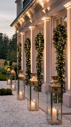 lighted lanterns are lined up on the side of a building in front of trees and bushes