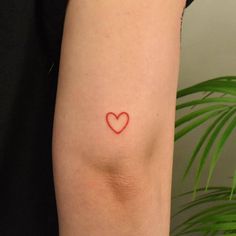 a small red heart tattoo on the arm