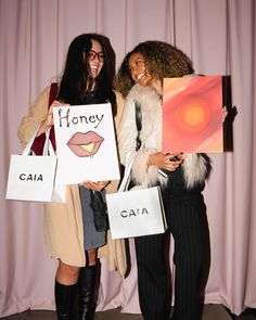 two women are holding shopping bags and posing for the camera with their faces painted on them