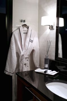 a robe hanging on the wall next to a sink in a bathroom with a mirror