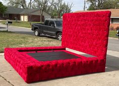 a large red bed sitting on the side of a road