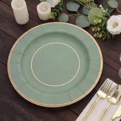 a green plate sitting on top of a wooden table next to silverware and flowers