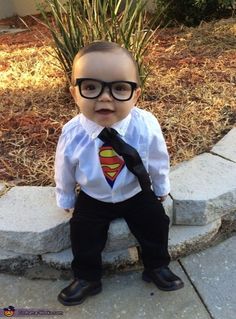 a little boy dressed up in a superman shirt and tie