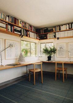 a room with two desks and bookshelves full of books