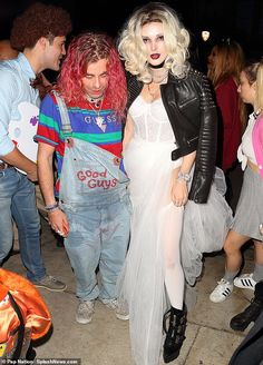 two women dressed up in costumes standing next to each other at a party with people looking on