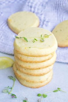 a stack of shortbread cookies sitting on top of a blue cloth next to lemon wedges