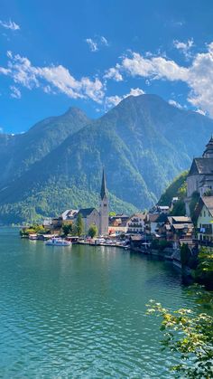 an old town sits on the shore of a lake with mountains in the back ground