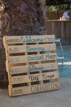 a wooden sign sitting on the side of a road next to a tall pole with writing on it