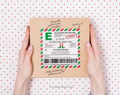 a person holding up a box with an e on it and the package is wrapped in red, green and white paper