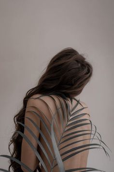 the back of a woman's body with palm leaves in front of her, against a white background