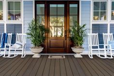 two white rocking chairs sitting on top of a wooden floor next to a door and windows