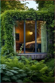 an open window in the side of a house covered in green plants and ivys