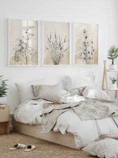 a bed with white sheets and pillows in a room next to two pictures on the wall