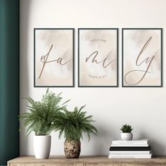 three framed art prints on a wall above a table with a potted plant and books