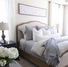 a bed with white pillows and blankets on top of it next to a window in a bedroom