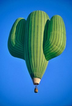 two large green hot air balloons flying in the blue sky with one big balloon attached to it's side