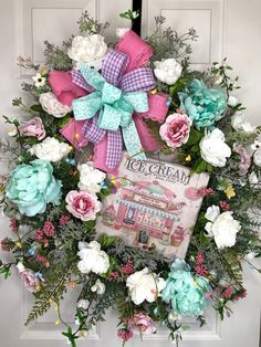 a wreath with pink, blue and white flowers is hanging on the front door as if it were an ice cream parlor