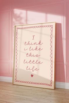 a pink room with a framed poster on the wall and a wooden floor in front of it that says i think like this little life