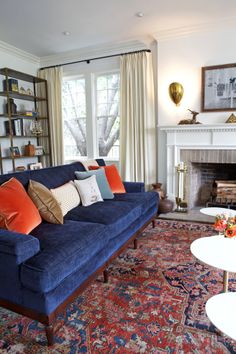 a living room filled with furniture and a fire place next to a large rug on top of a hard wood floor