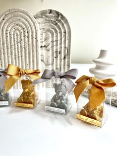 four small glass vases with gold and silver decorations in them on a white table