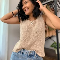 a woman standing in front of a rack with clothes on her shoulders and smiling at the camera