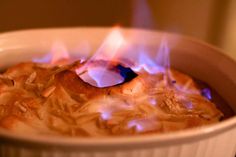 a white bowl filled with food on top of a stove covered in fire and flames