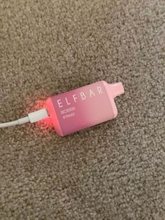 an electric toothbrush plugged in to a charger on the floor with a pink light